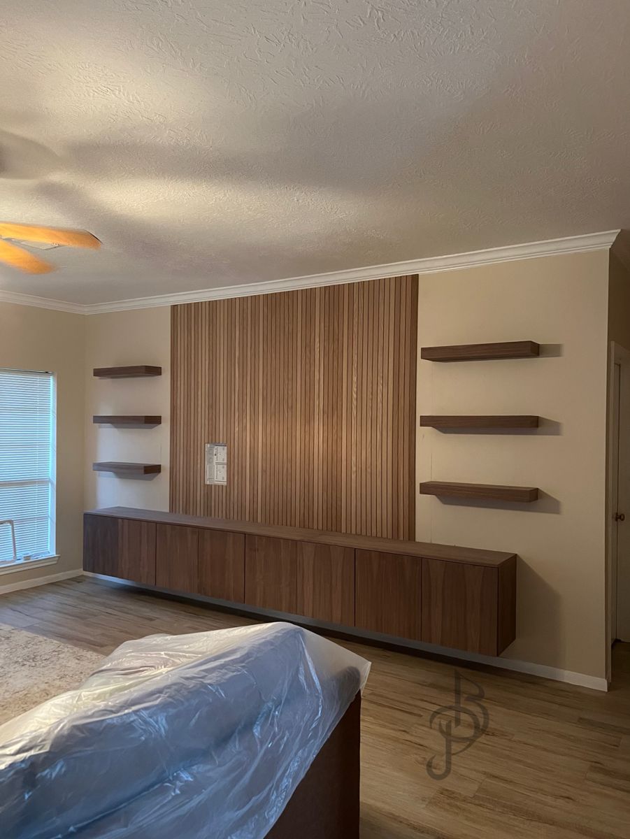 Finished media wall with walnut slat paneling, floating shelves, and a floating console
