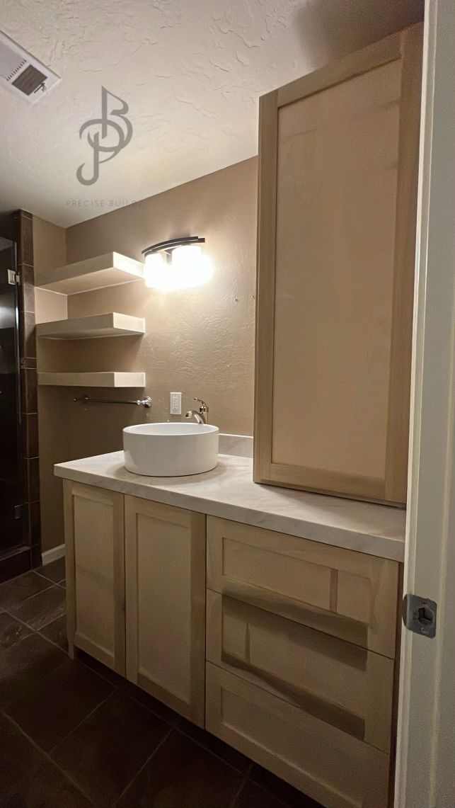 Bathroom vanity wall with floating corner shelves, sconce lighting, and a vessel sink