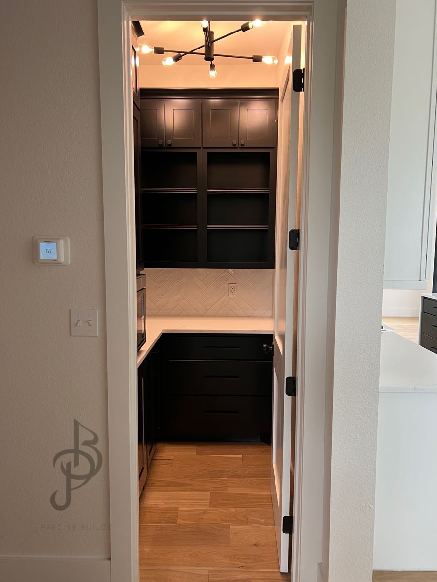 Butler's pantry with black shaker cabinetry, white quartz counters, and a white herringbone tile backsplash