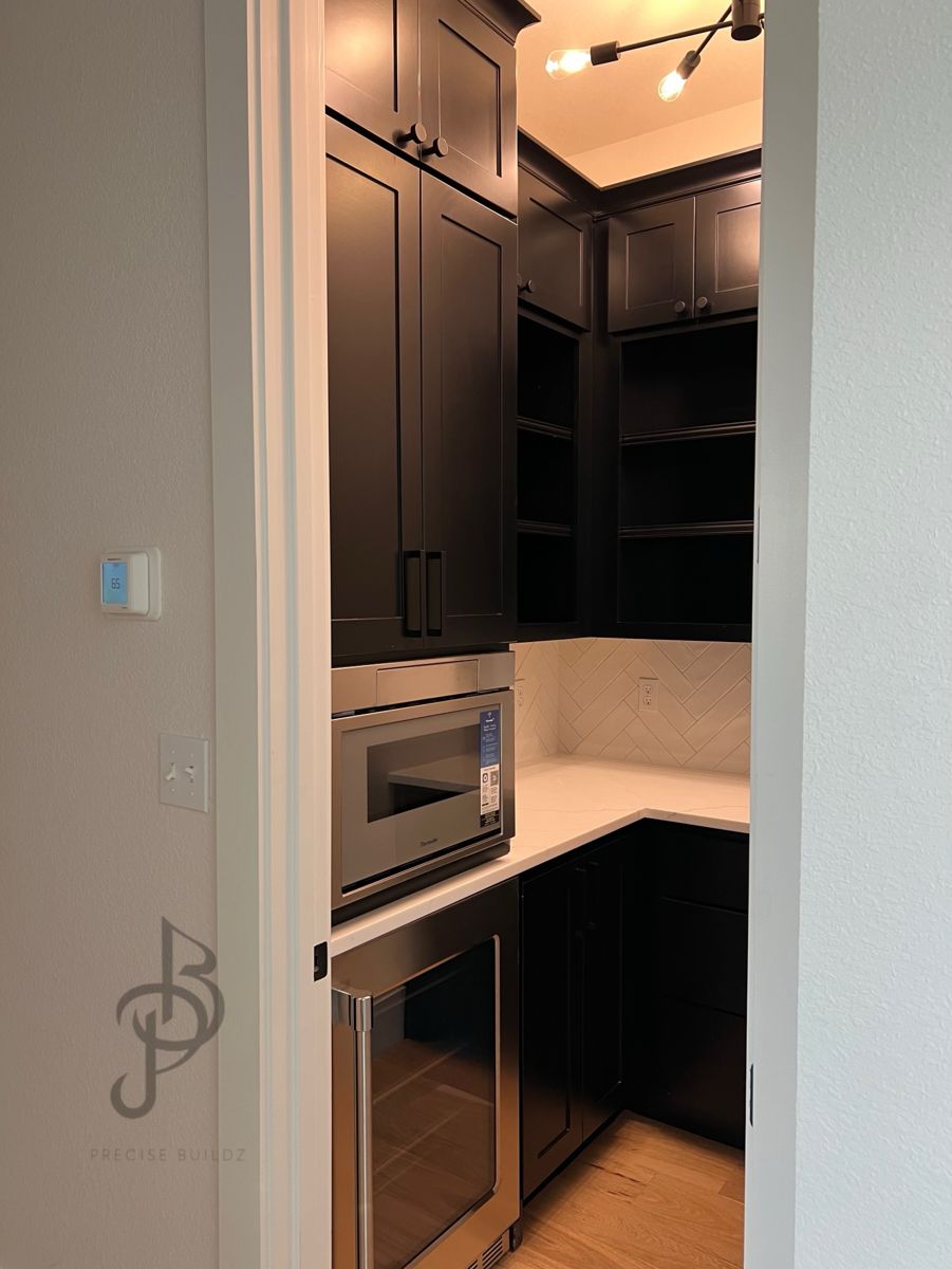 Black pantry cabinetry with a built-in stainless microwave and glass-front beverage fridge