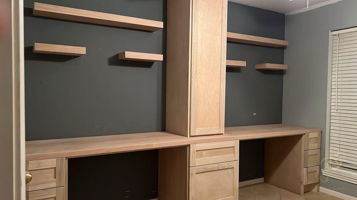 Custom built-in desk with drawer bays and floating shelves during pre-finish fit-up