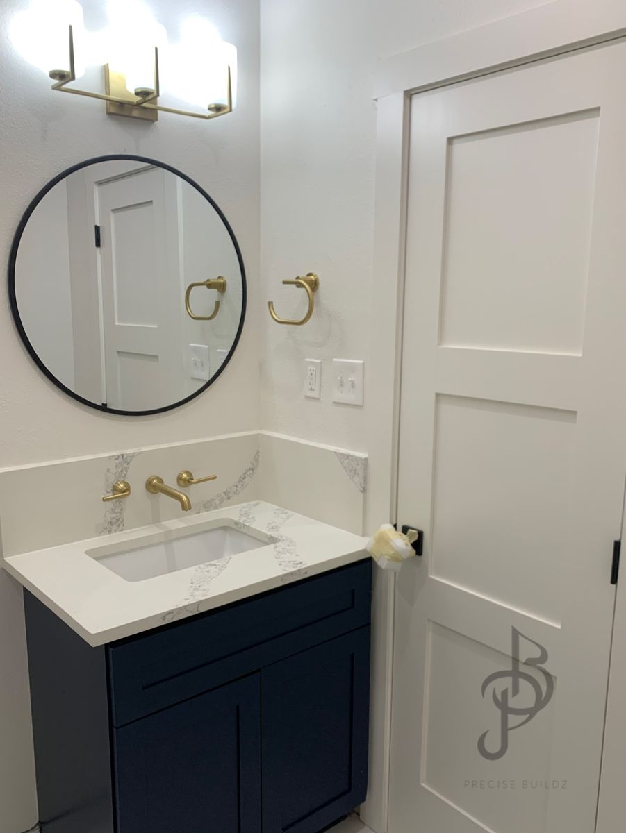 Custom navy blue powder room vanity with white quartz top and gold faucet