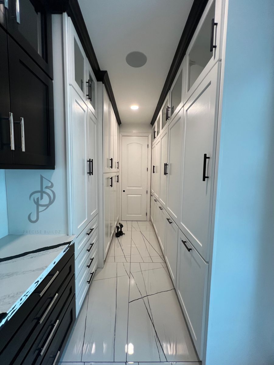 Walk-through closet corridor featuring custom dark grey shaker cabinets and veined white marble floors