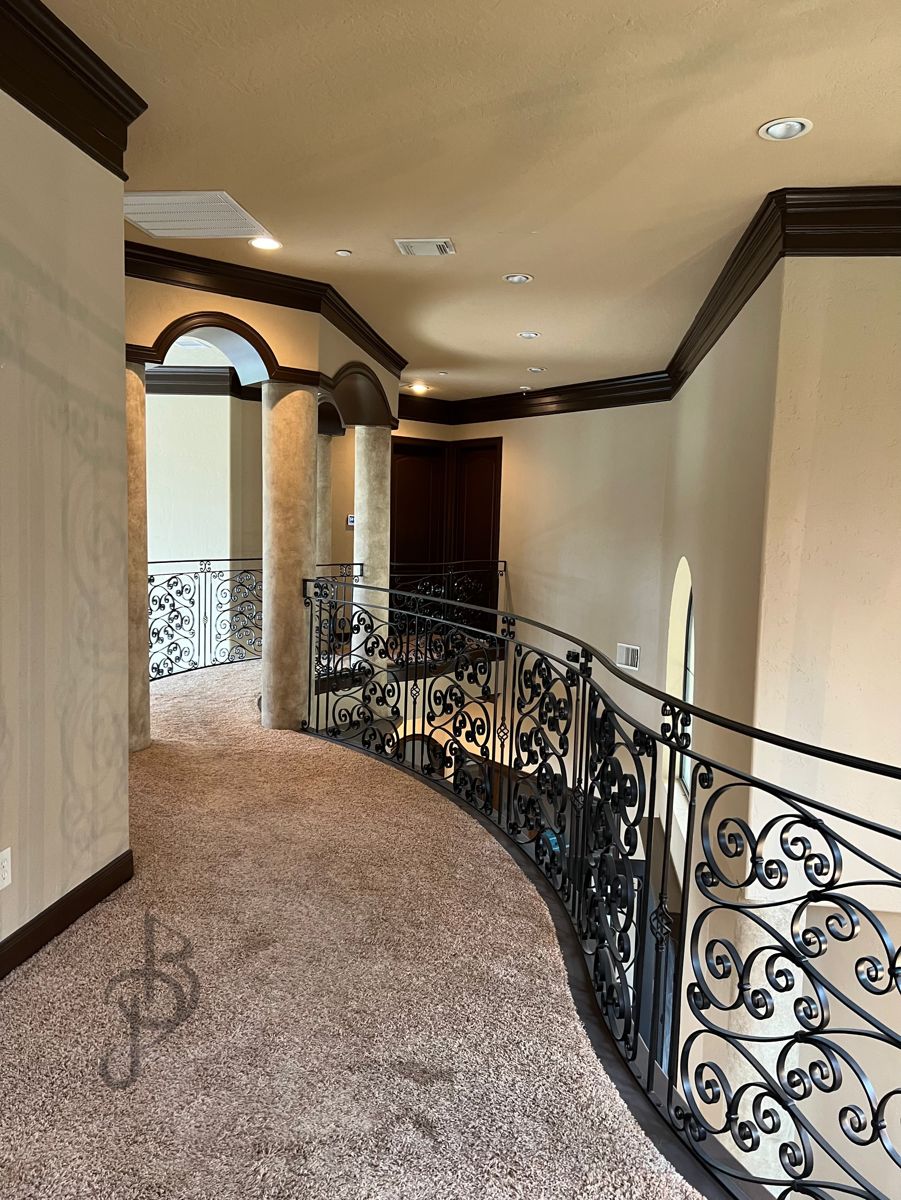 Grand curved landing with a custom wrought iron balustrade