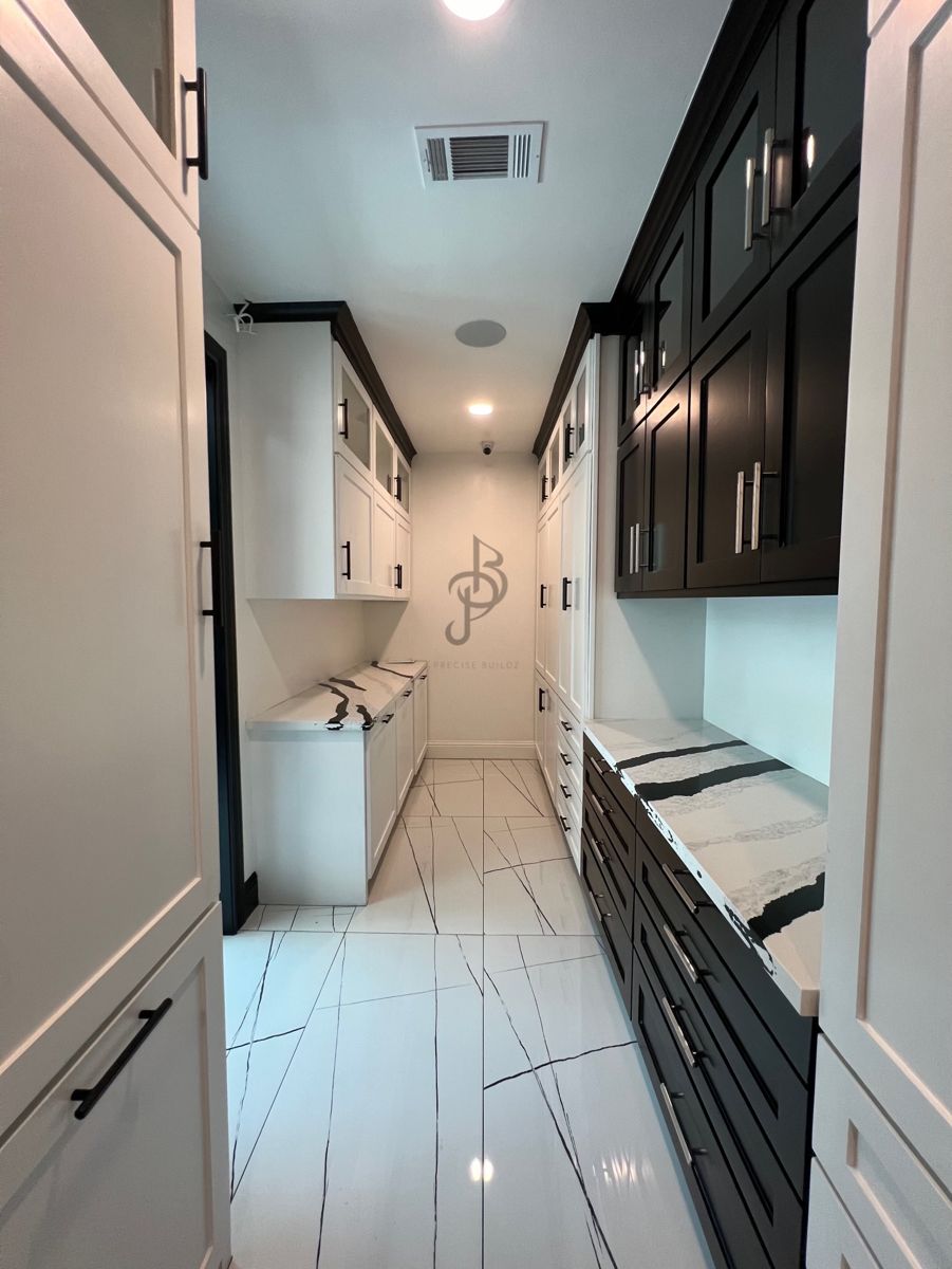 Finished butler's pantry with white and dark cabinetry and marble floors