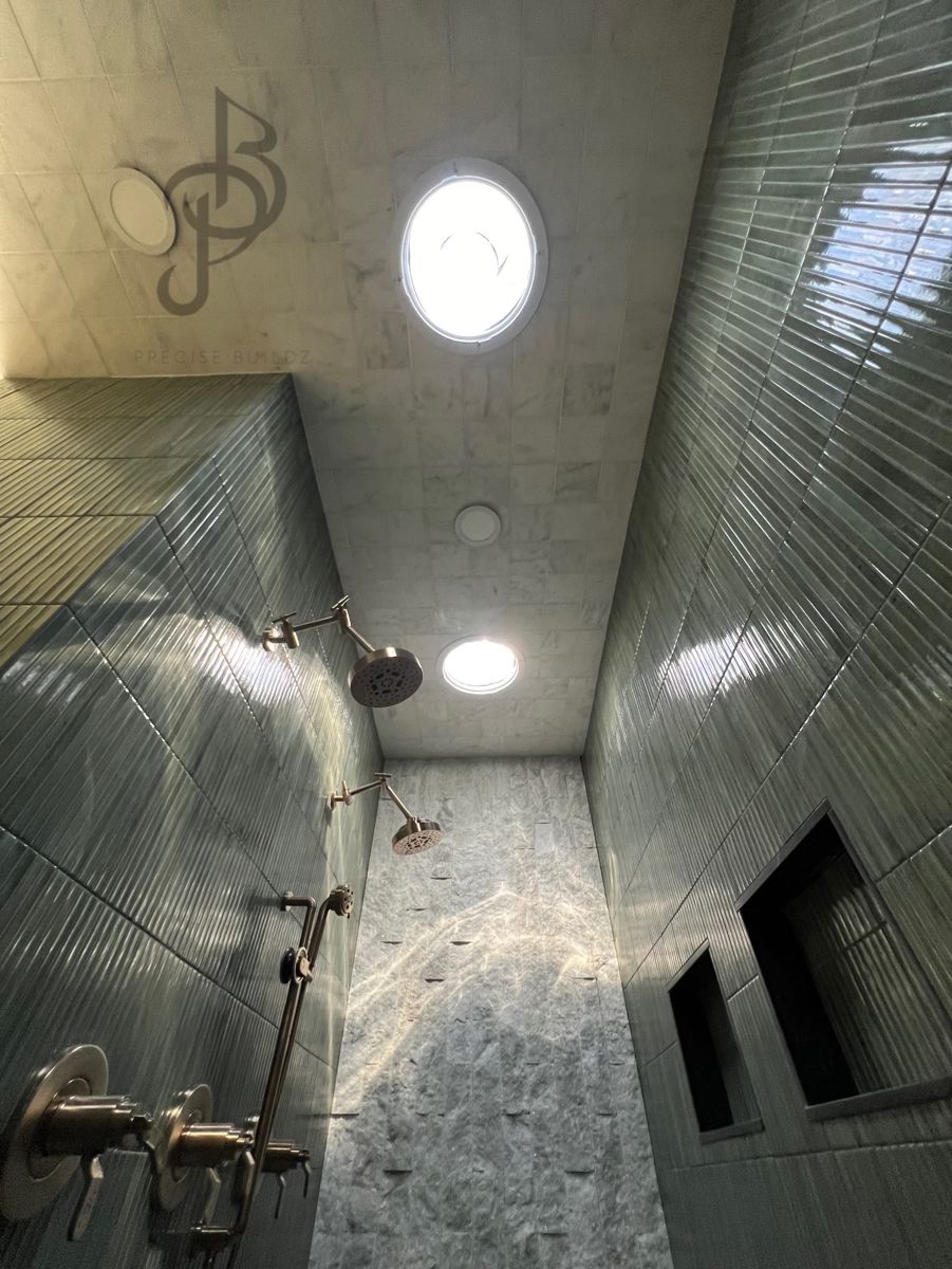 Luxury walk-in shower with marble accent wall, dual shower heads, and brass fixtures