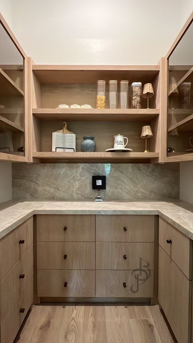 Bespoke white oak walk-in pantry with glass doors and natural stone counters